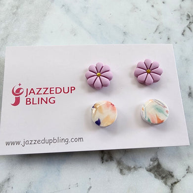Two pairs of polymer clay stud earrings, one lavender floral and one pastel marble.