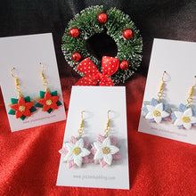 Load image into Gallery viewer, Handmade poinsettia Christmas earrings in red, pink, and blue with gold-colored hooks, displayed with festive wreath background.
