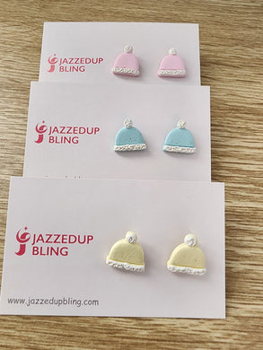 Set of three pastel polymer clay beanie earrings in pink, blue, and yellow with white trim and pom-poms, handmade by Jazzed Up Bling in New Zealand.