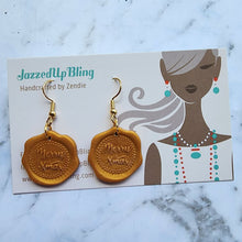 Load image into Gallery viewer, Handmade gold polymer clay wax seal earrings with Merry Xmas design by Jazzed Up Bling.
